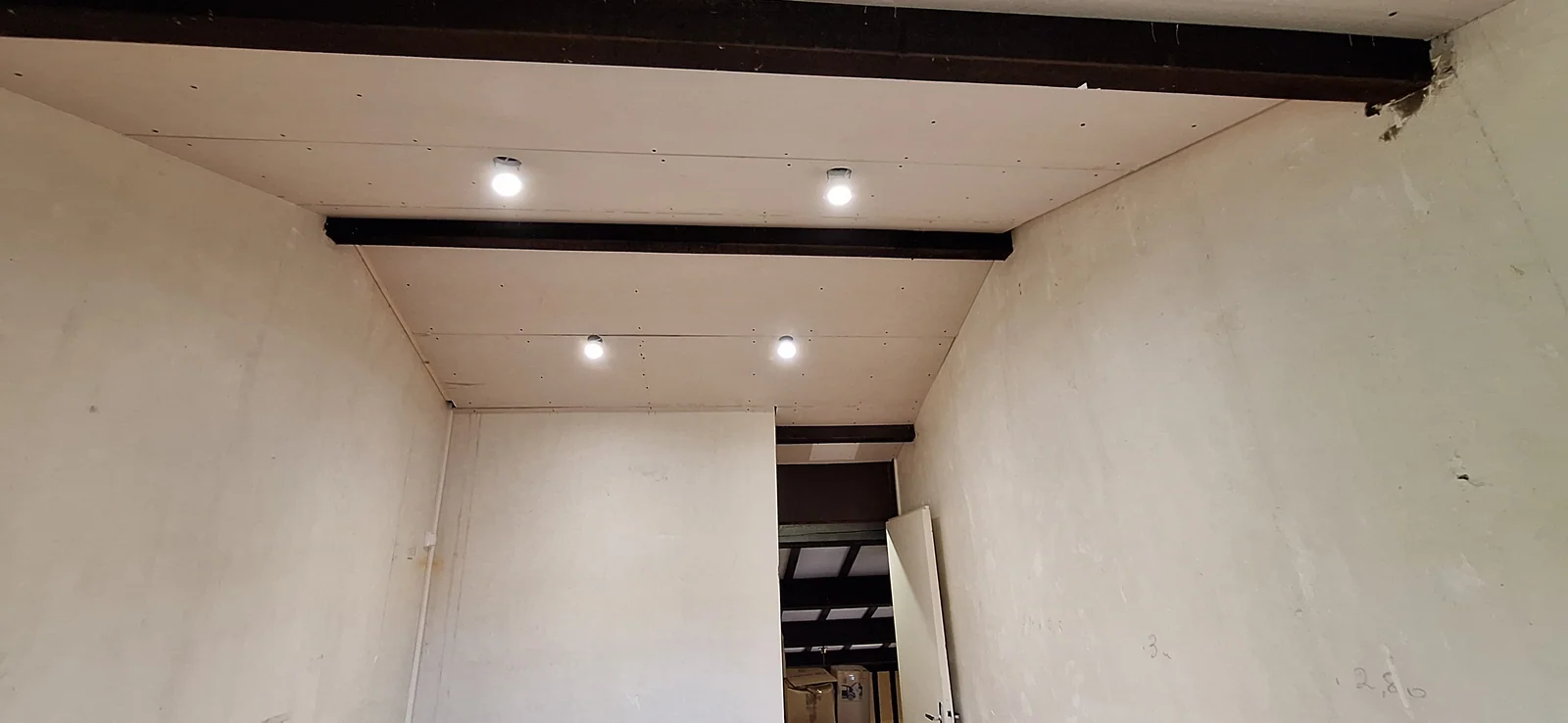Quatre spots encastrés allumés au plafond de l’étage d’une maison en rénovation à Libourne